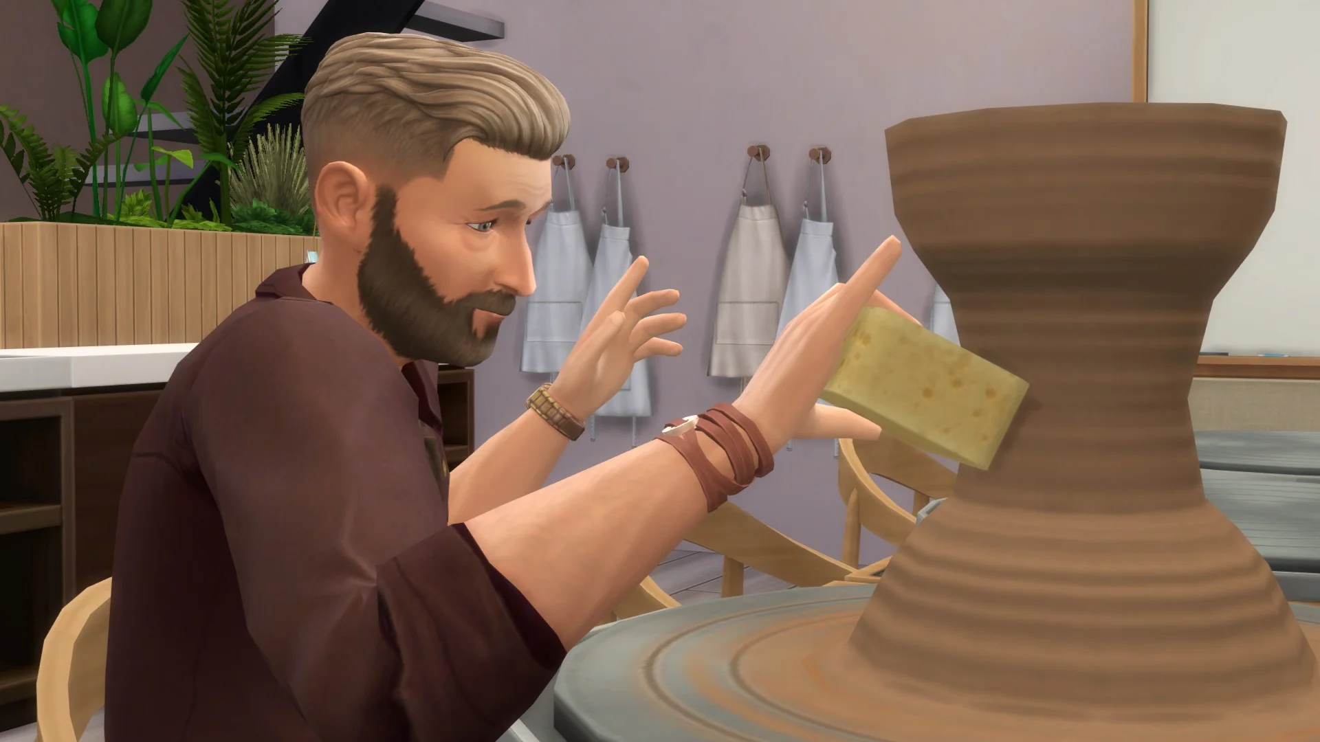 A sim brushes a pot with a sponge on a pottery wheel